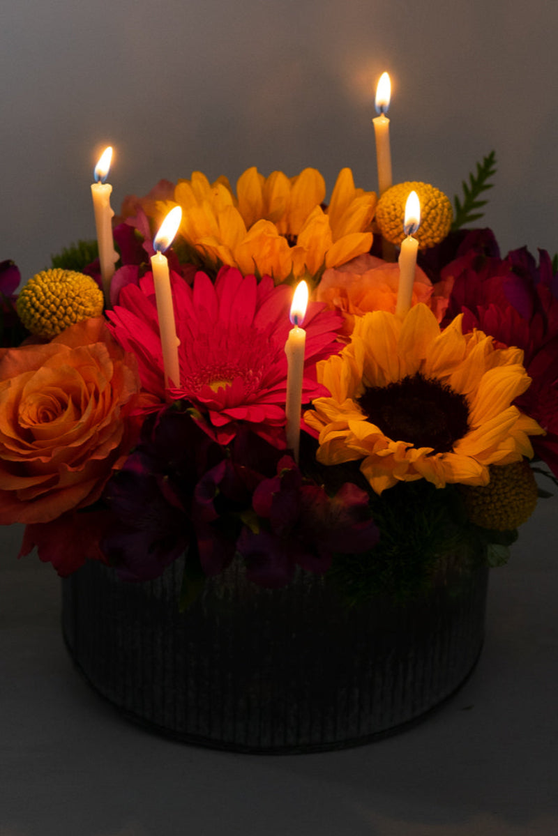 lights out version of flower birthday cake with candles lit