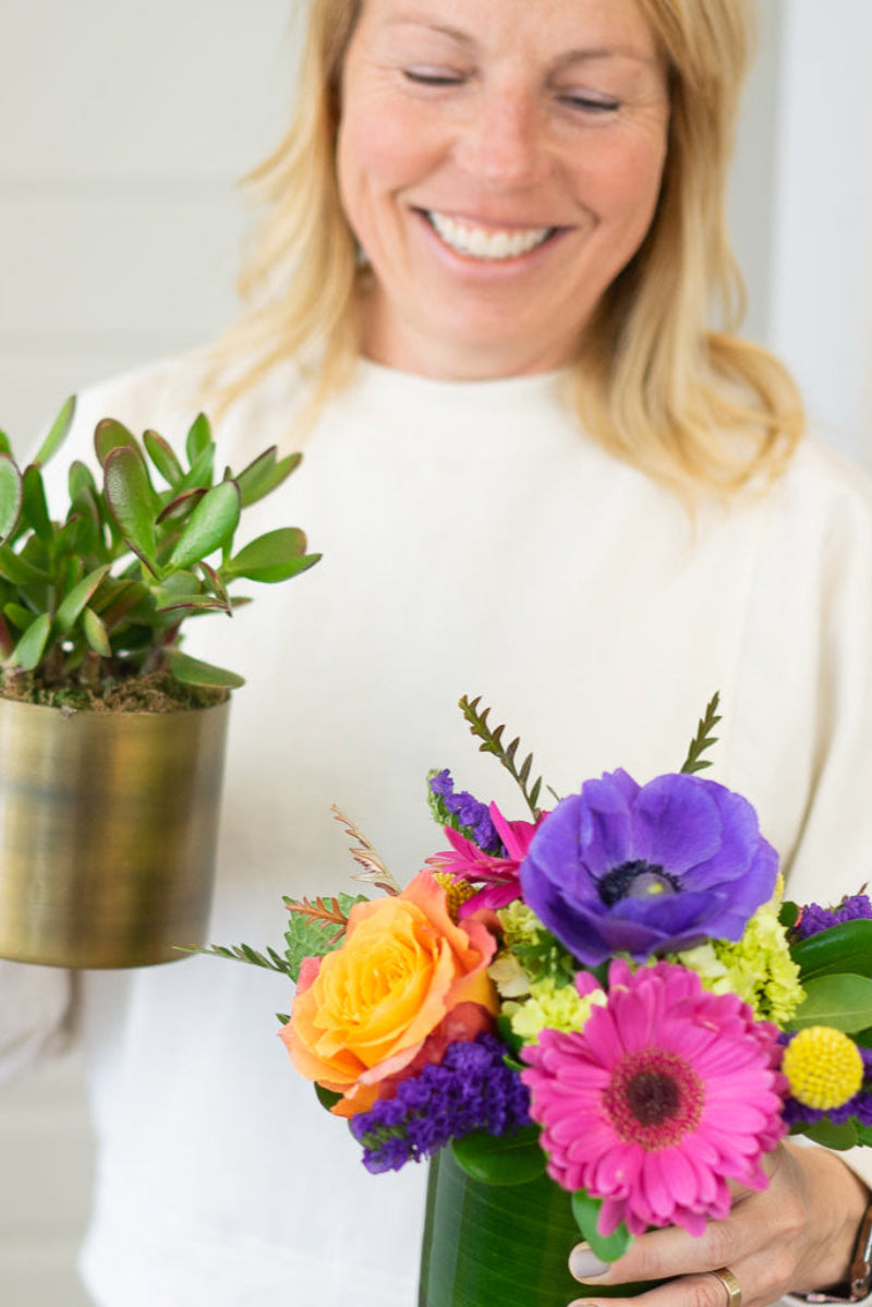 the shop owner and designer holding a colorful designers choice bouquet
