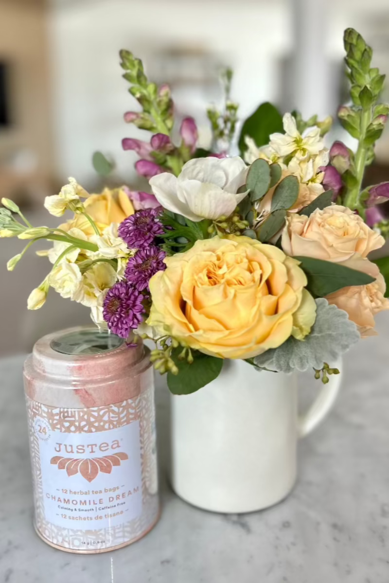 flower arrangement in mug with tea tin on counter