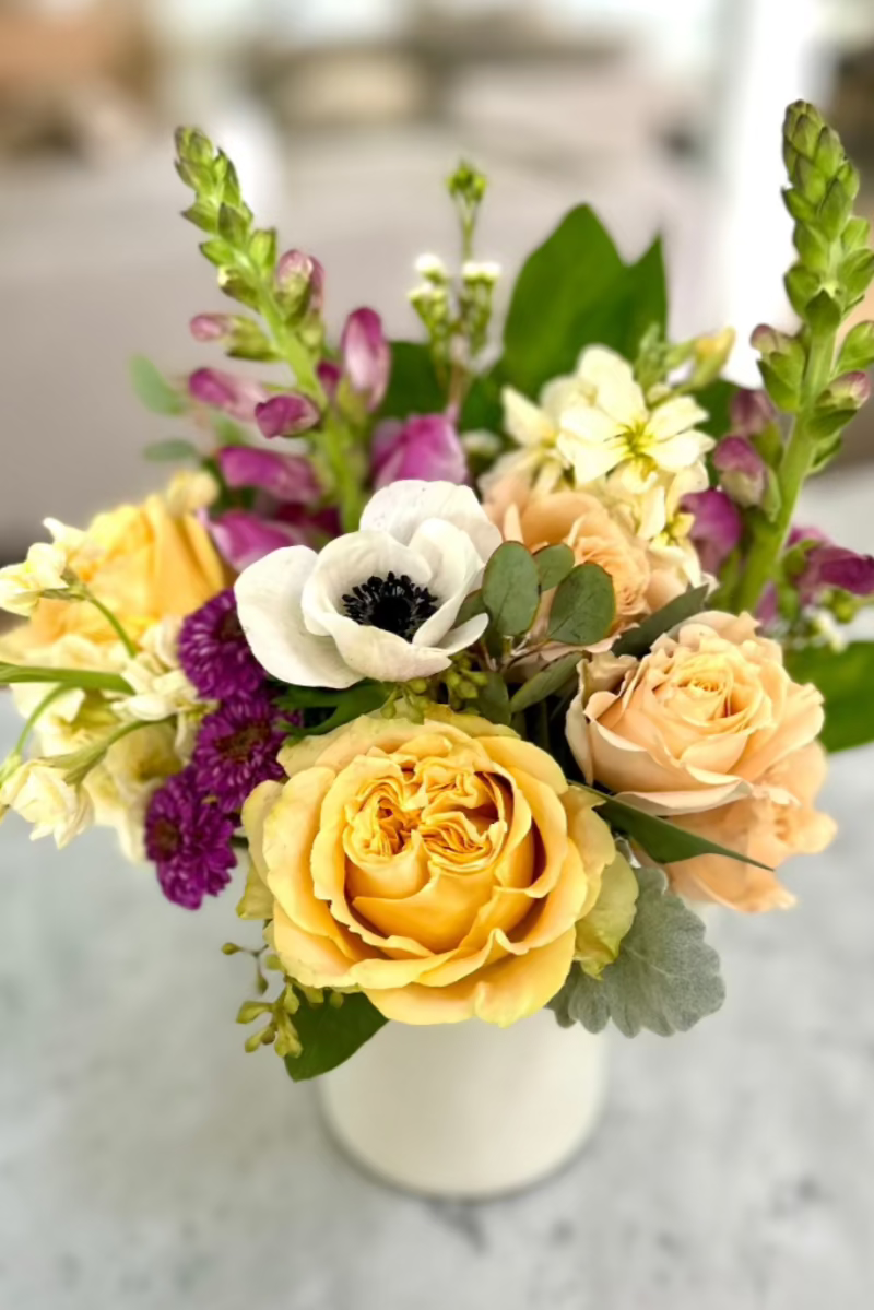 close up of roses anemone snapdragons mixed bouquet in tea mug on counter 
