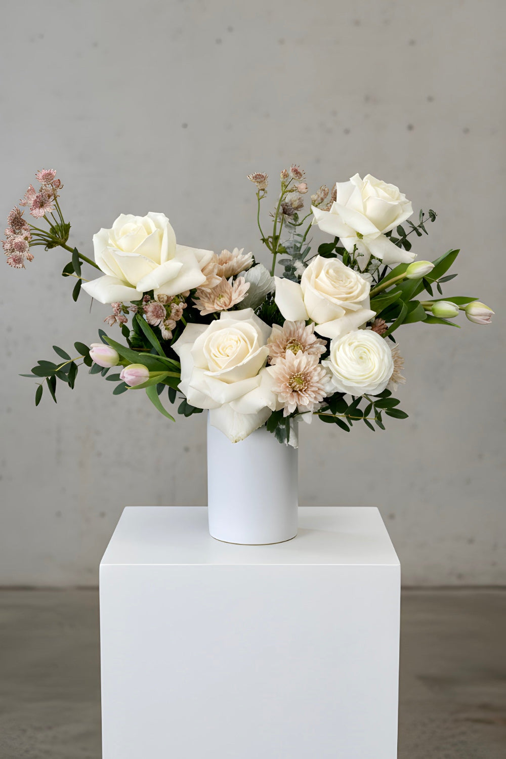Bouquet of white and beige flowers in a white vase on a light gray background