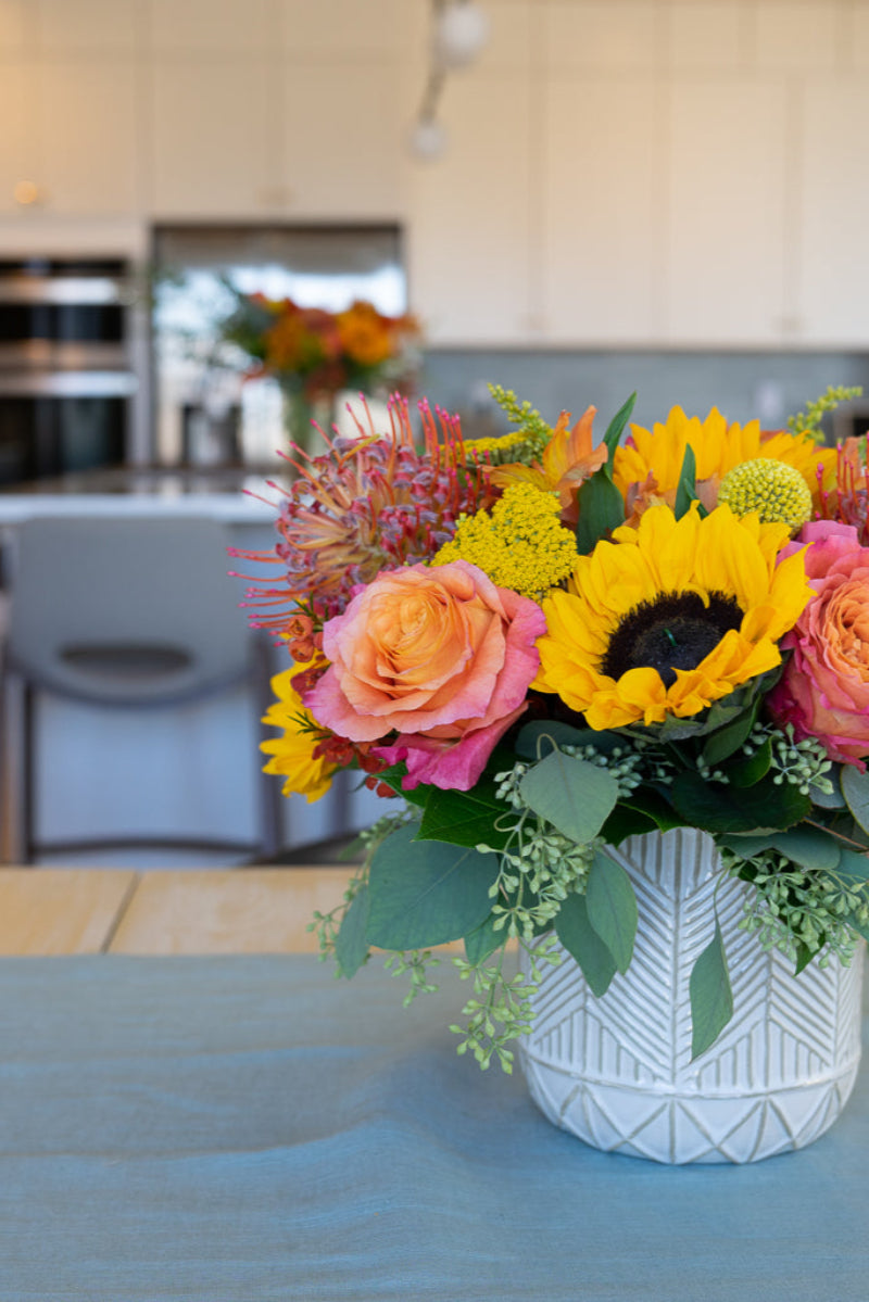 sunflowres, roses, protea flower bouquet on dining room table 
