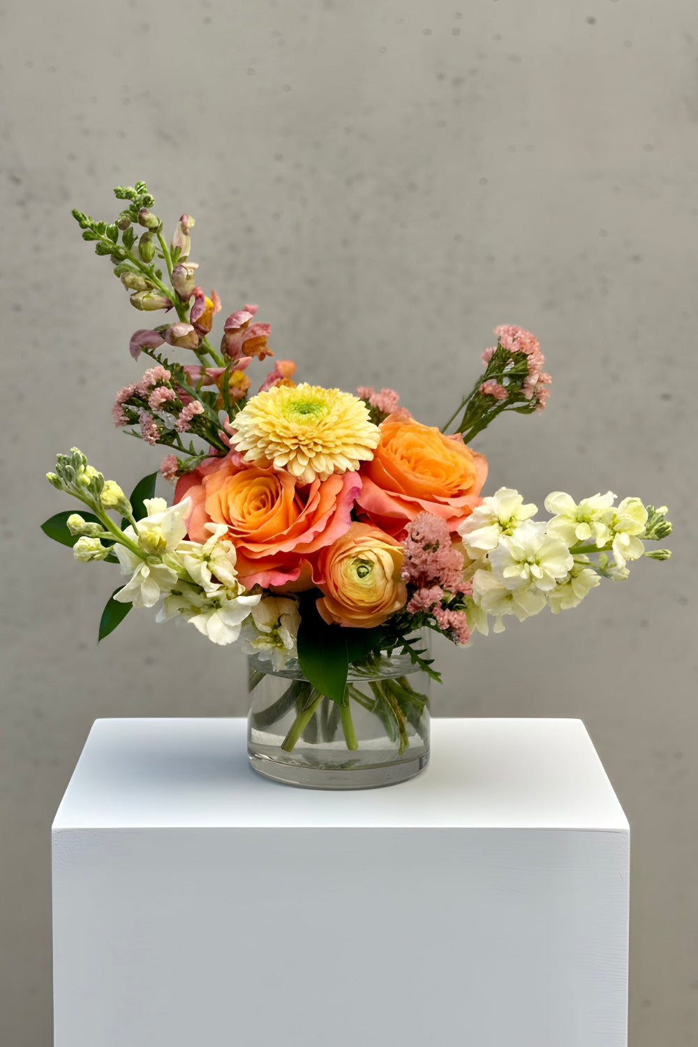 Petite Treat size Apricot Honey bouquet featuring yellow stock, coral roses, and ranunculus with fresh greenery in a compact, modern arrangement.