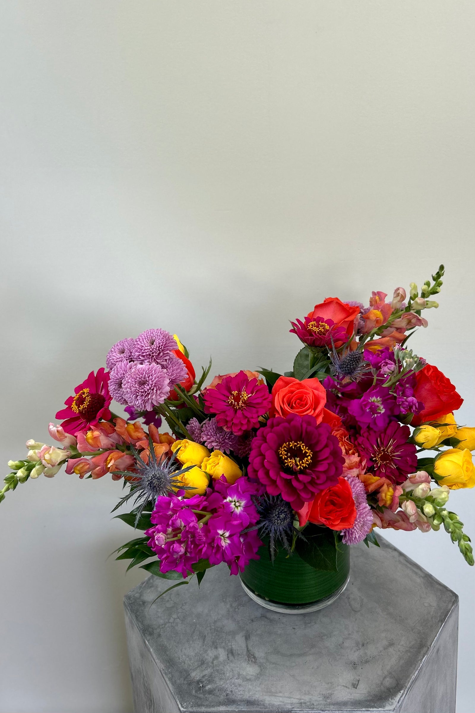 Bloomfetti signature bouquet with lavender, coral, hot pink, bright yellow blooms like roses, stock, snapdragons, zinnias in a clear glass vase