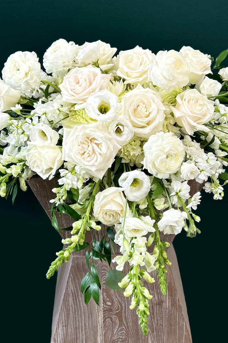 Bouquet of white flowers in a wooden vase against a dark background