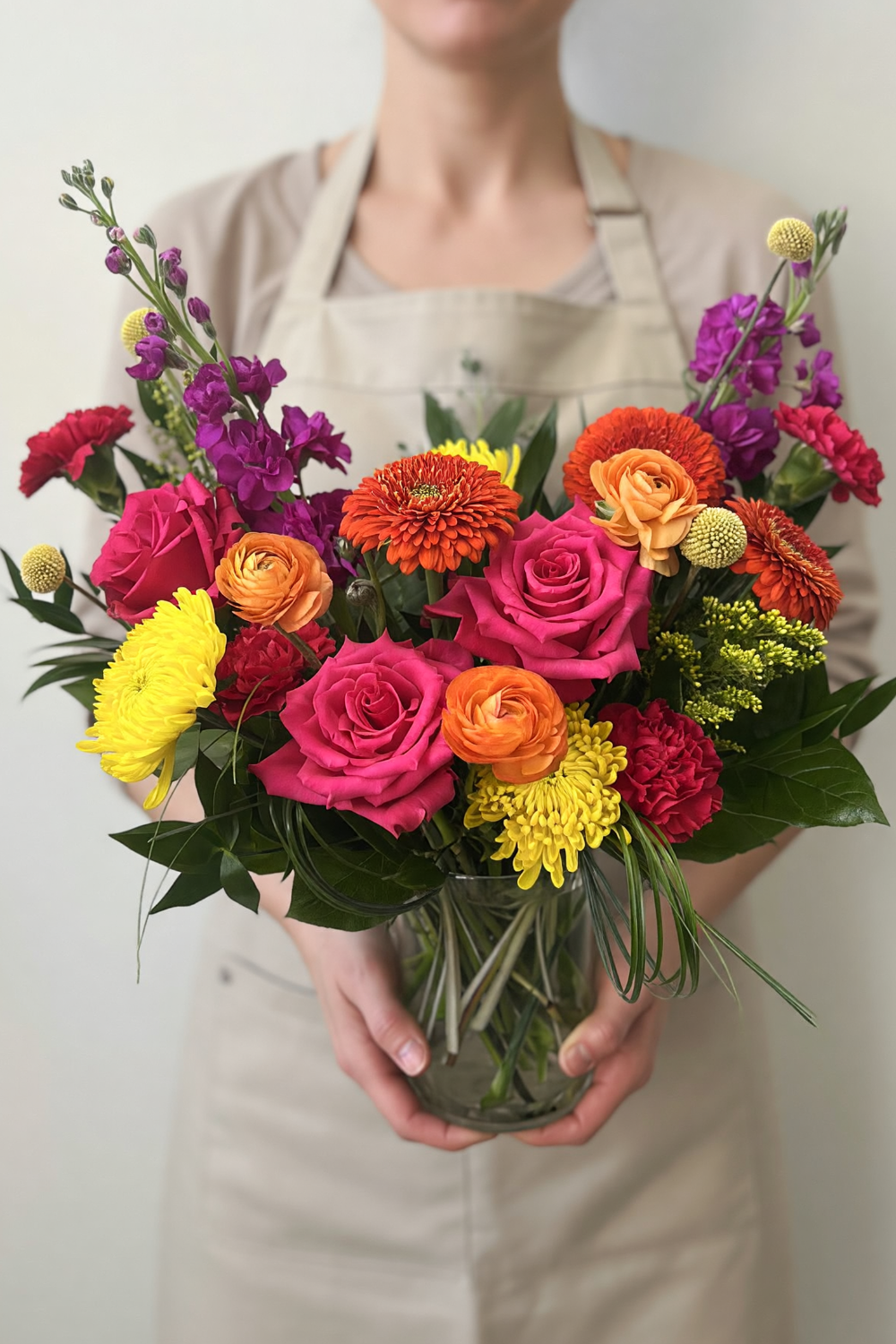  Classic Citrus Pop bouquet displayed on a coffee table with abundant, colorful spring blooms being held by florist