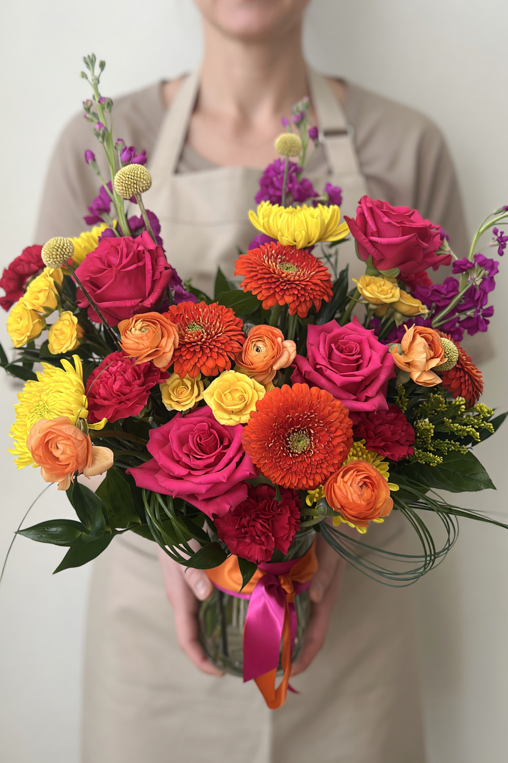 Florist holding a Premium Citrus Pop bouquet with lush, vibrant citrus‑inspired flowers.