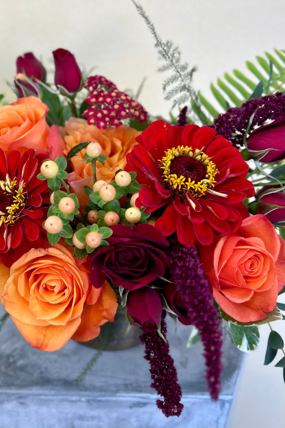 Close‑up of Crimson Gathering Bouquet showing roses, hypericum berries, and textured fall foliage