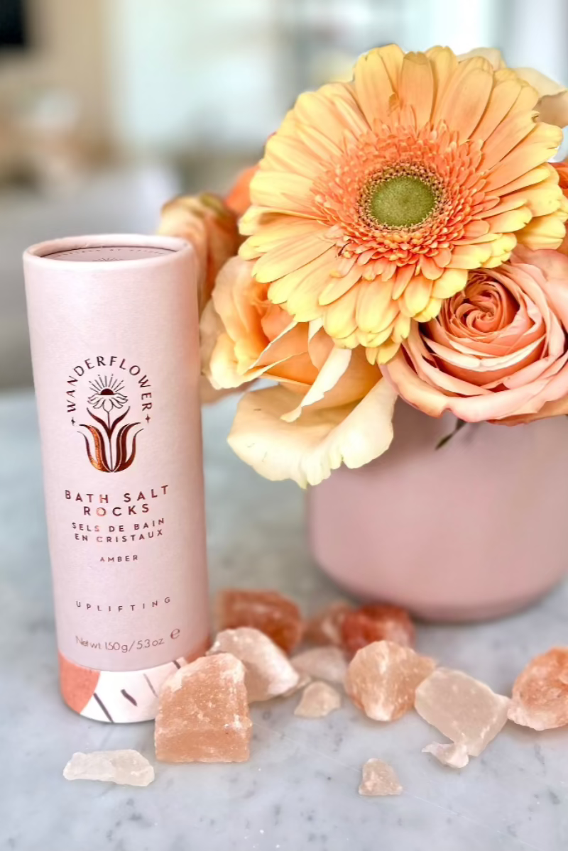 soft pink and peach flowers with canister of bath salt rocks