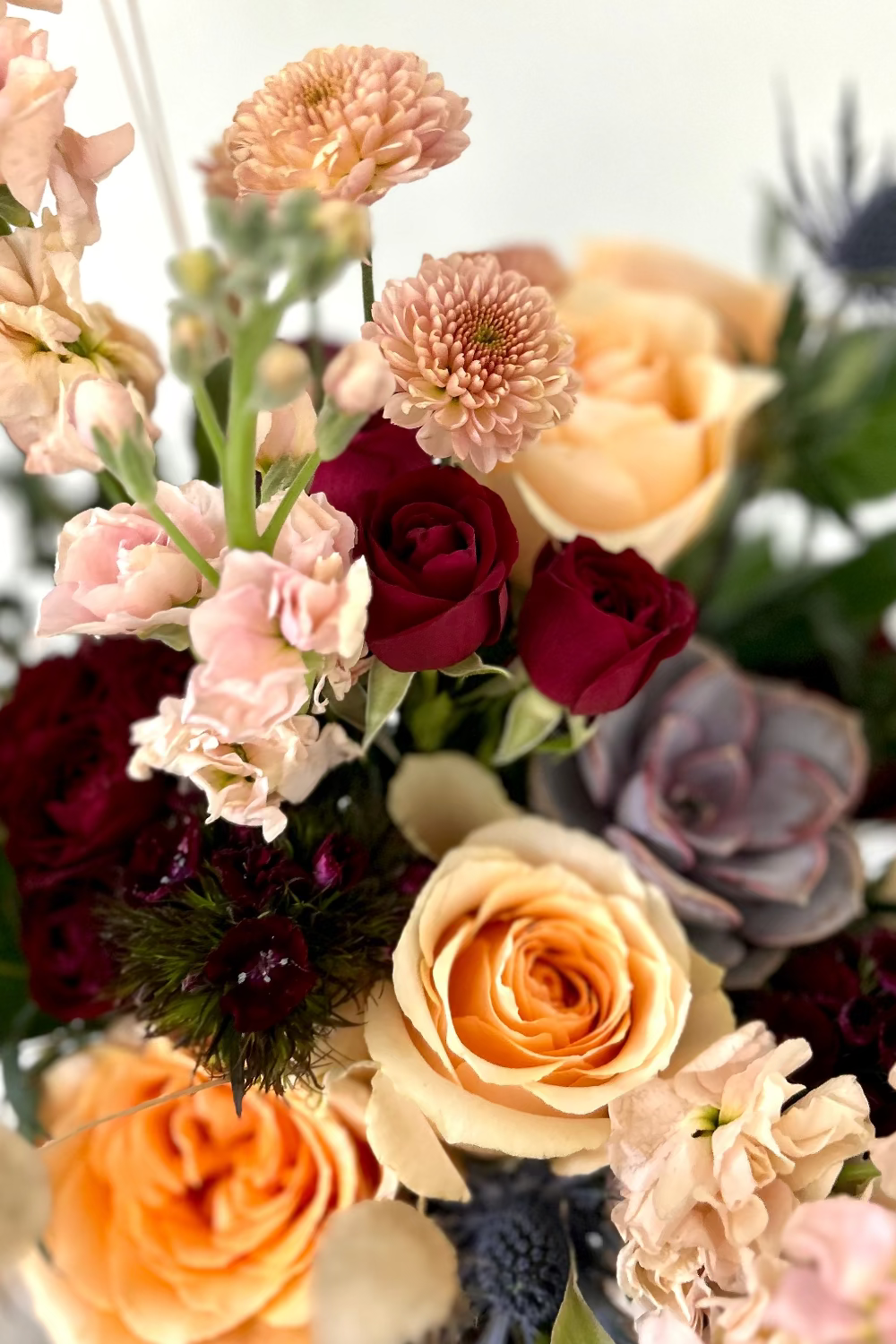 A vibrant bouquet of various flowers including pink roses, red roses, orange roses, and other mixed flowers, arranged together in a clear vase.