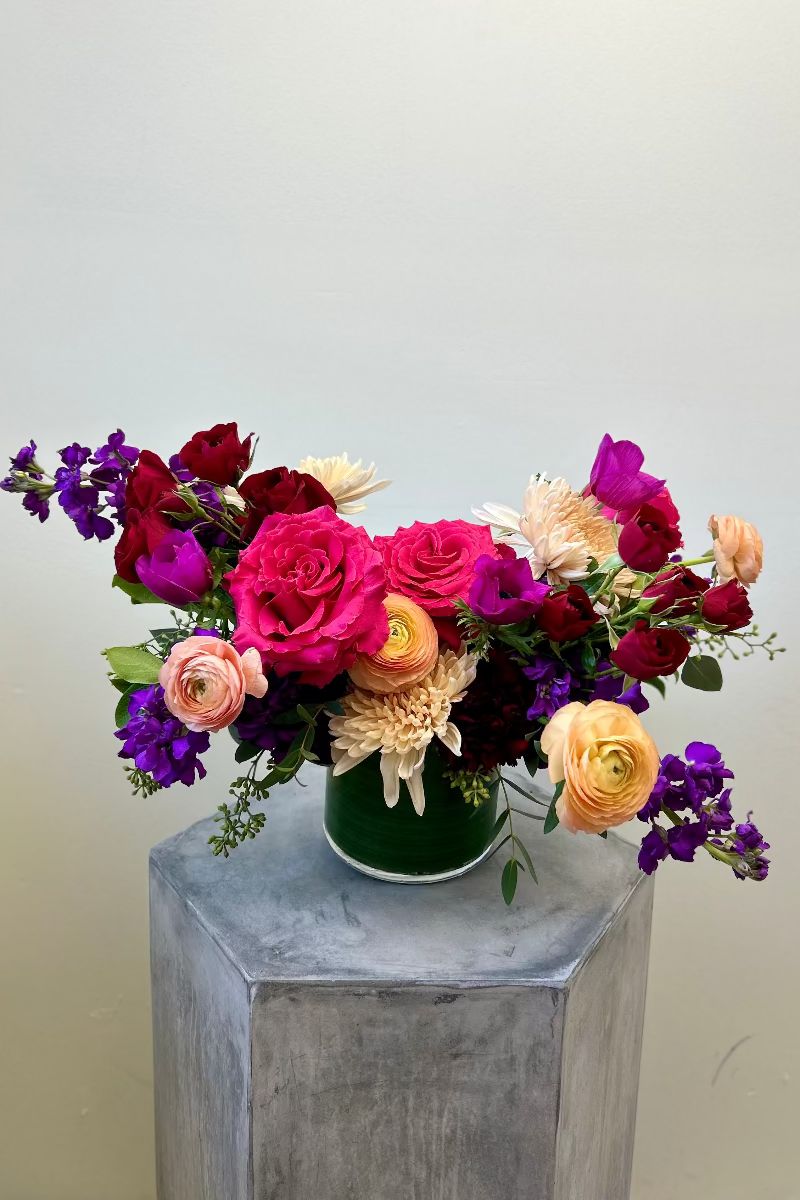 Fleur Noire signature bouquet with hot pink roses, magenta anemones, peach ranunculus, and burgundy spray roses in a loose, airy design