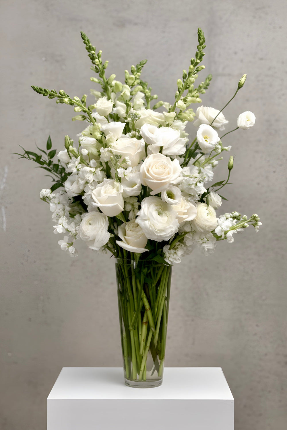 soft white flowers designed in tall glass vase with roses, snapdragons, lisianthus