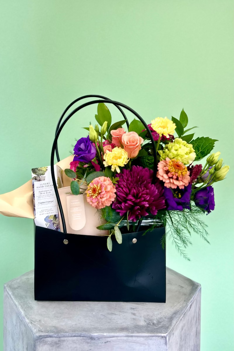 Glow &amp; Bloom gift bundle with cheerful bouquet, candle, and hand cream in black handled gift bag for gifting
