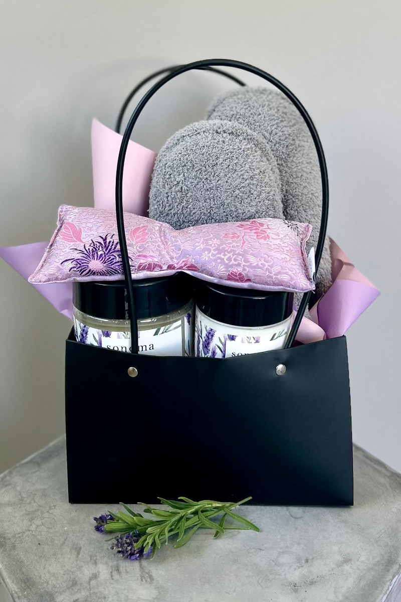 Lavender Embrace bouquet and spa gifts arranged in a stylish gift bag with pretty tissue paper, ready for delivery