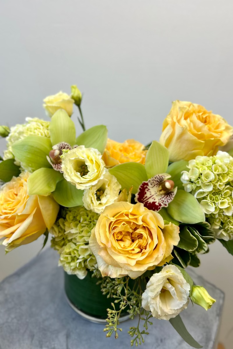 Close-up of Lemon &amp; Light bouquet showing soft yellow blooms, green cymbidiums, and textured foliage