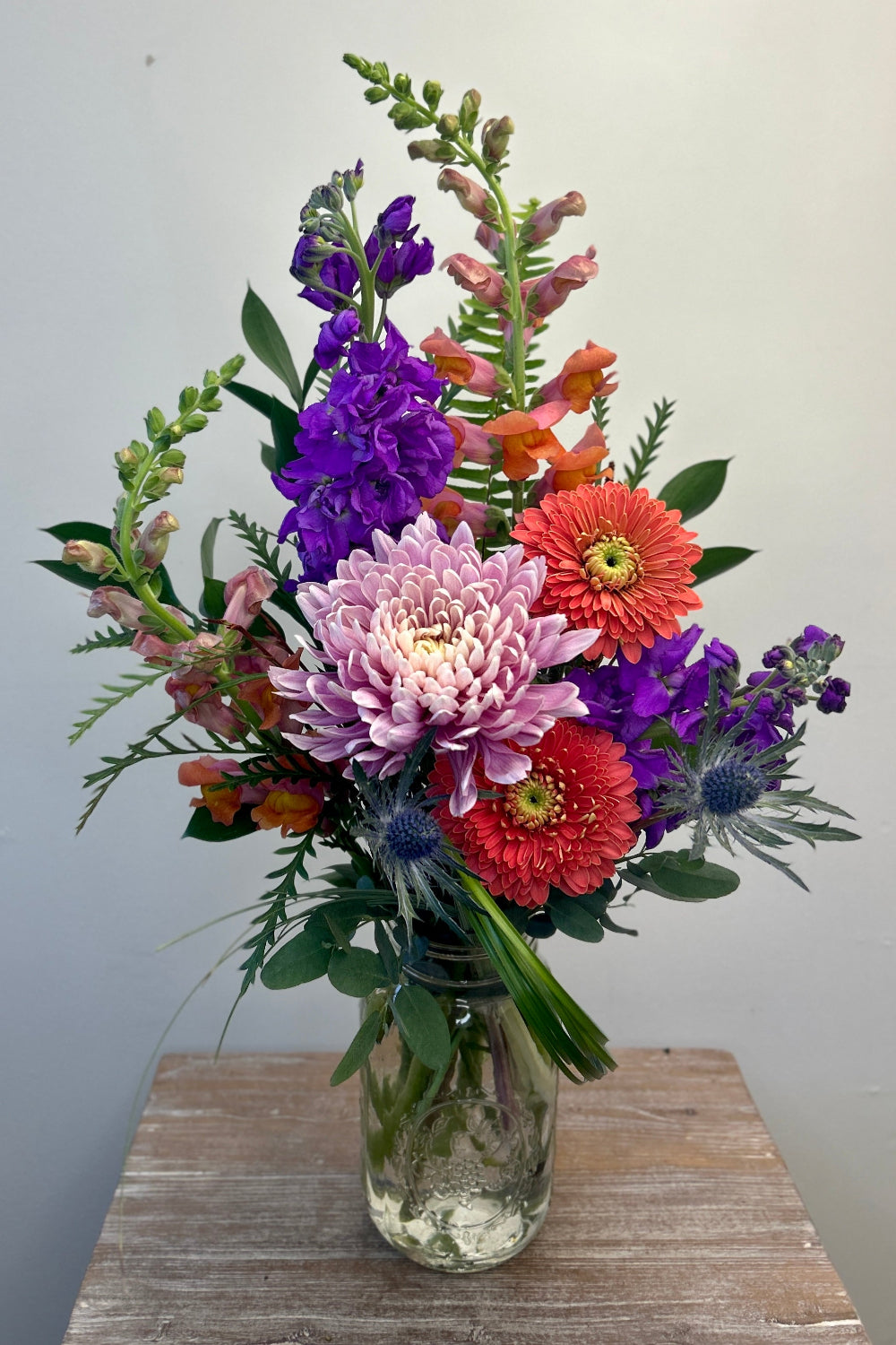budget friendly bouquet with peach gerbera daisies, stock, snapdragons, cremone, thistle and fun foliage 