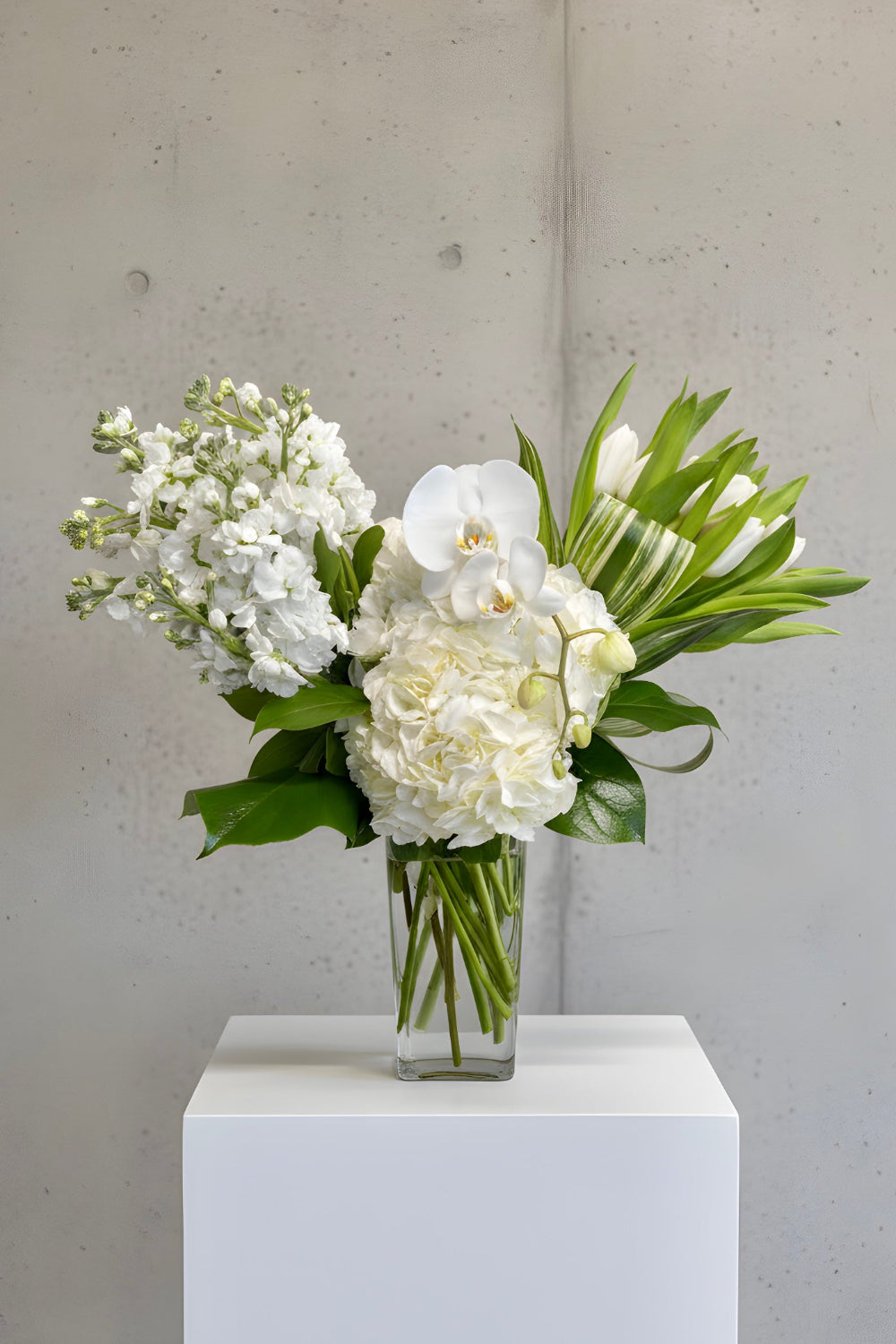 Bouquet of white flowers in a clear vase Artistic  bouquet with premium flowers and sculptural foliage