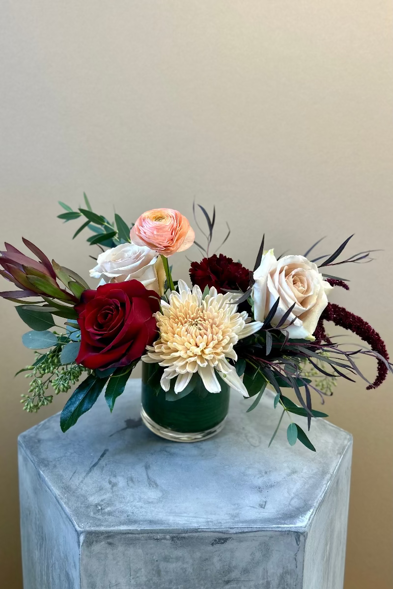 Petite Rosé Ember bouquet on a side table featuring blush roses, burgundy safari sunset, and soft eucalyptus in a modern, compact design