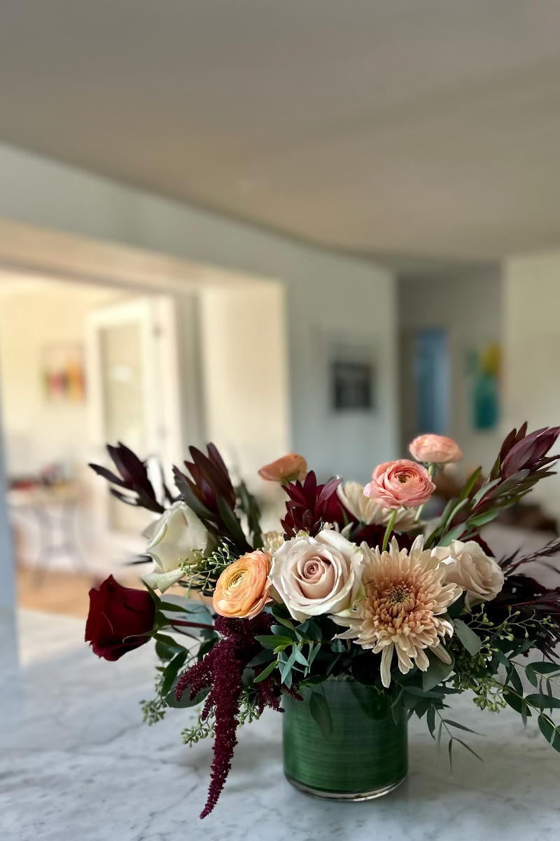 Rosé Ember signature bouquet displayed on a table with natural light highlighting rich tones and airy textures