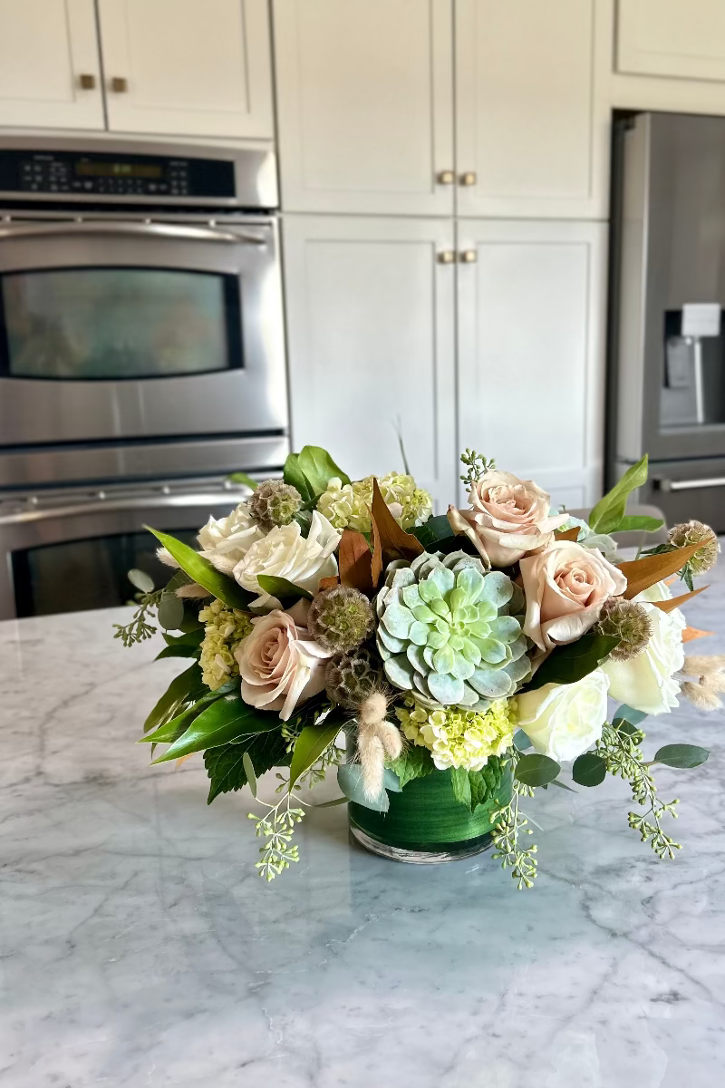 Stillness and Sage bouquet displayed on a kitchen island with natural light highlighting neutral tones and soft greens