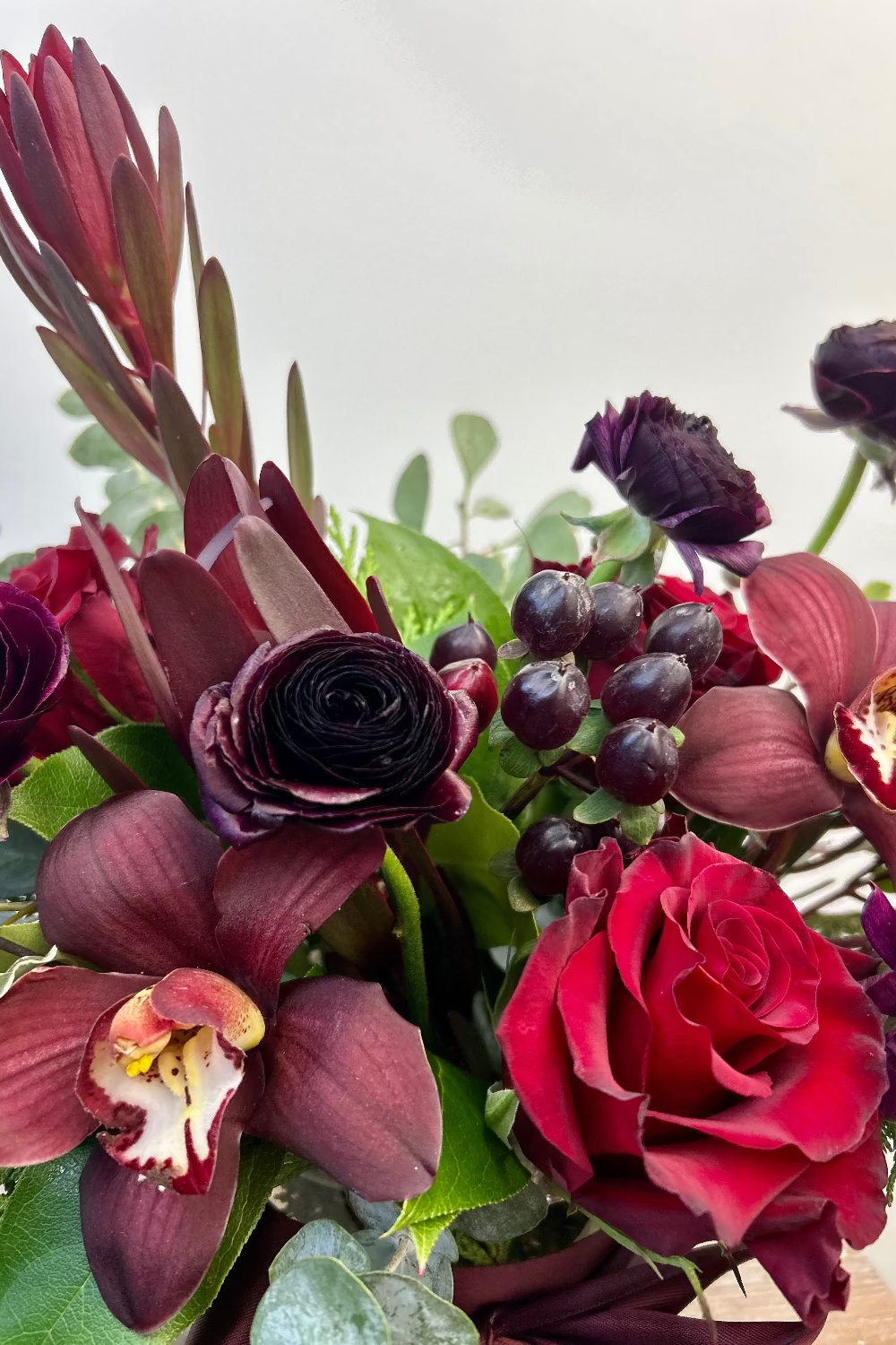 Close-up of plum and burgundy flowers with evergreen accents