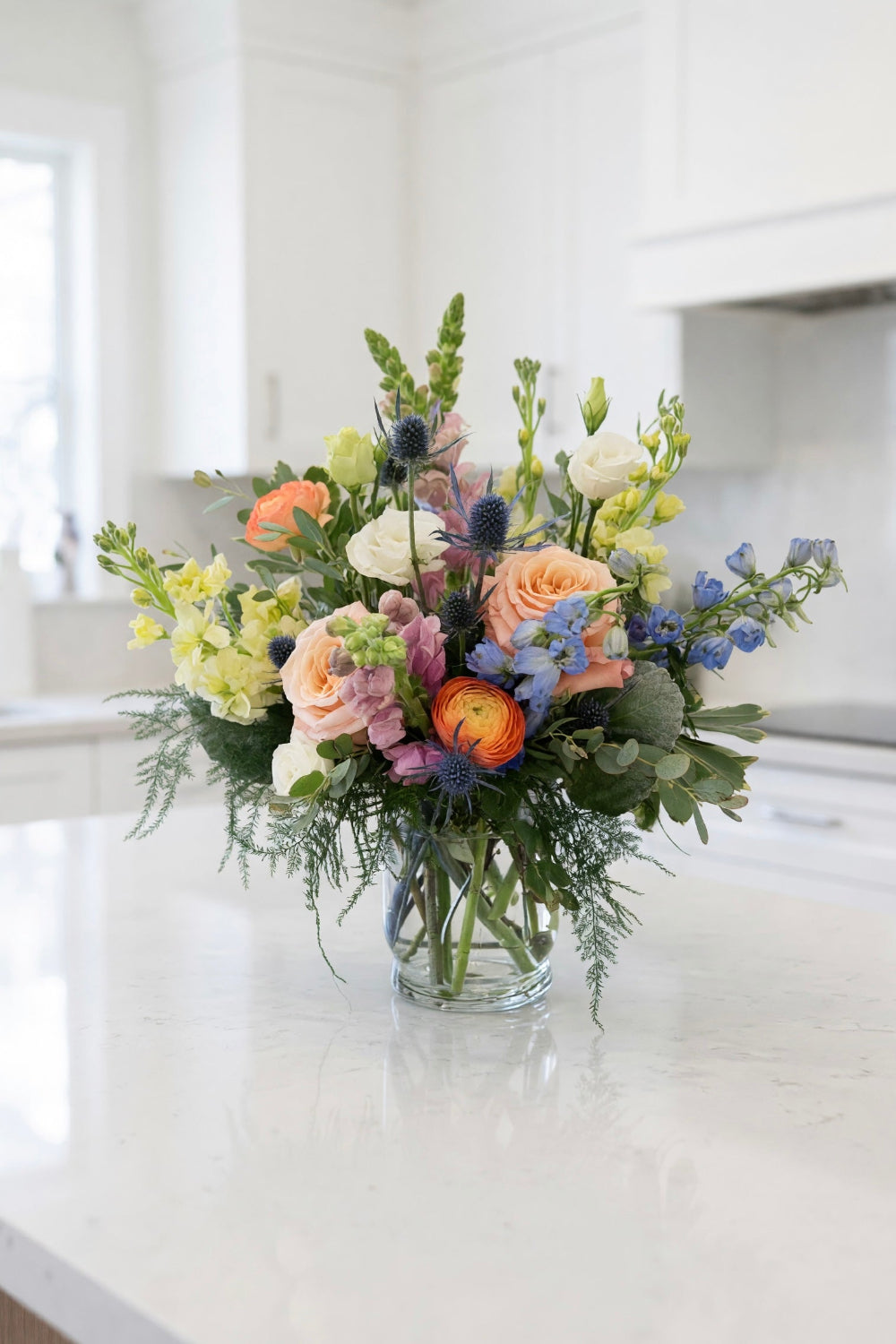 Summer Sorbet pastel flower bouquet displayed on a kitchen island, featuring airy summer blooms like stock, delphinium, snapdragons, lisianthus, ranunculus, and eucalyptus.
