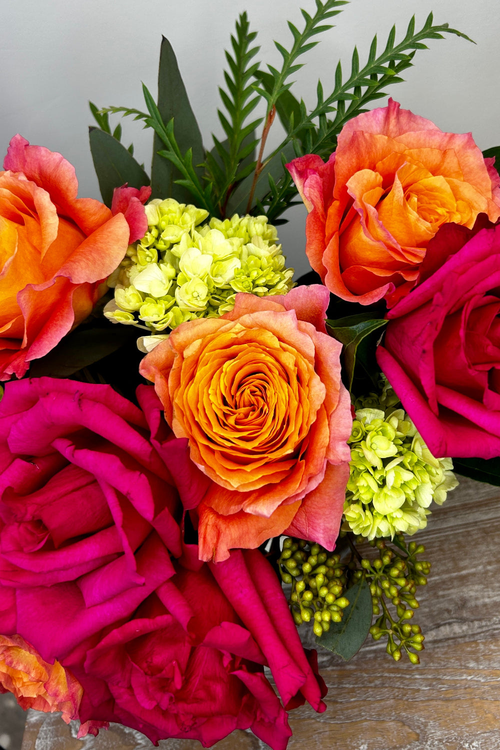Close‑up of hot pink roses, Free Spirit coral roses, and green hydrangea from the Sunset Spark bouquet, showcasing premium blooms for local flower delivery.