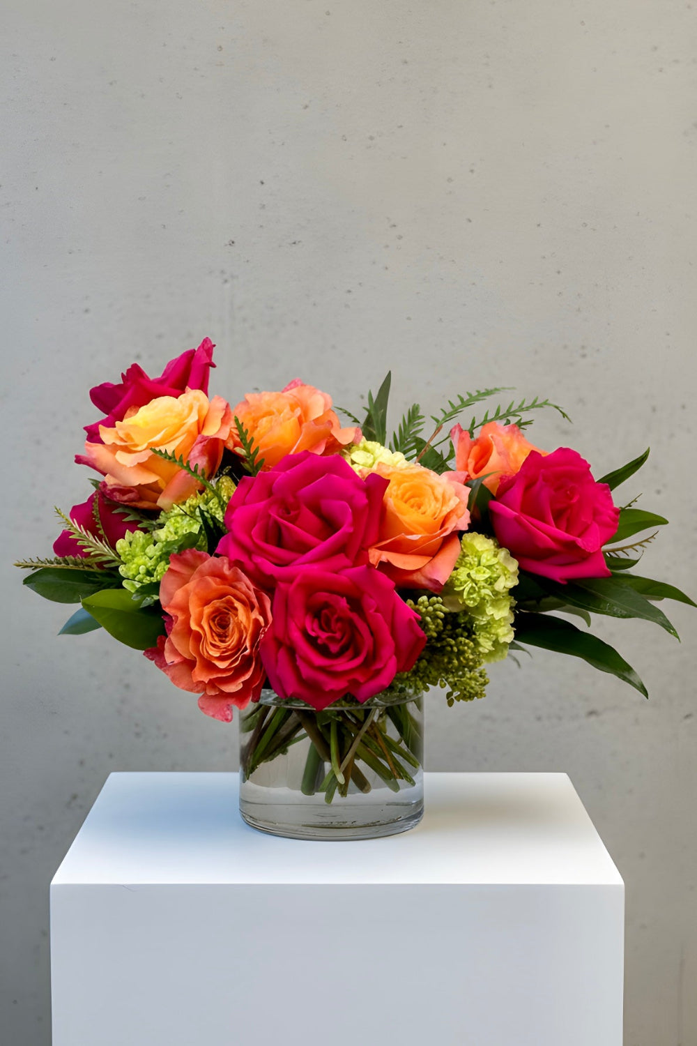 Sunset Spark bouquet with hot pink roses, coral Free Spirit roses, and green hydrangea in a modern floral design.