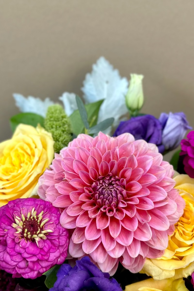 close up of low summer garden flower arrangement styled on dining table with lush, colorful blooms