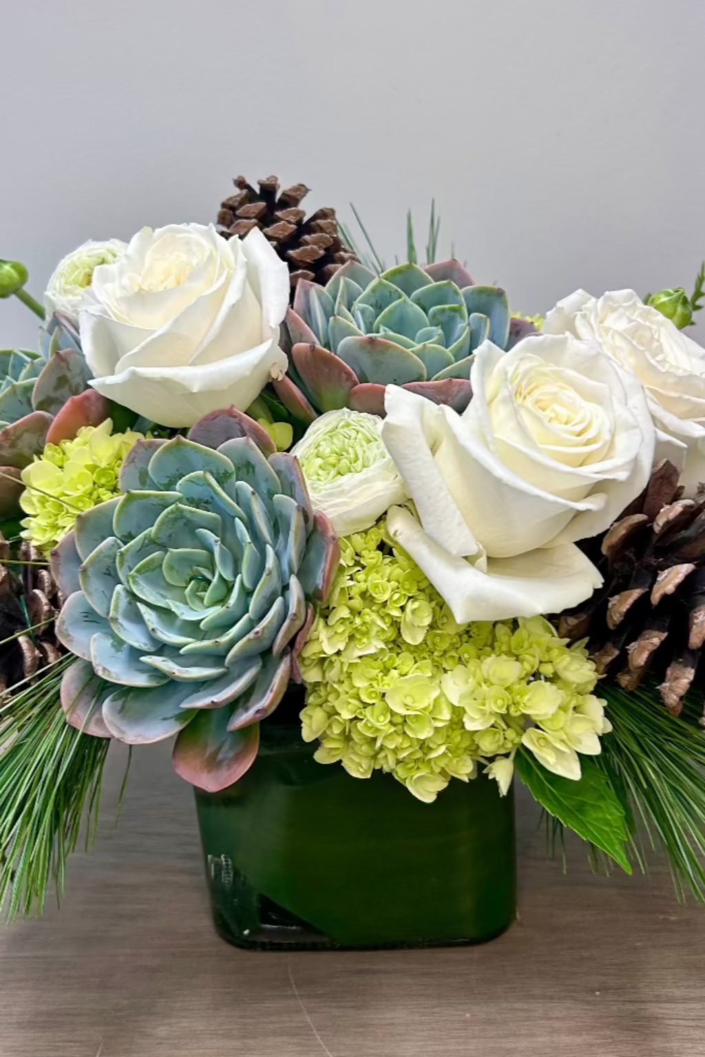 white roses succulents white ranunculus pine cones evergreens designed by a woman owned local castle pines florist the flower fix