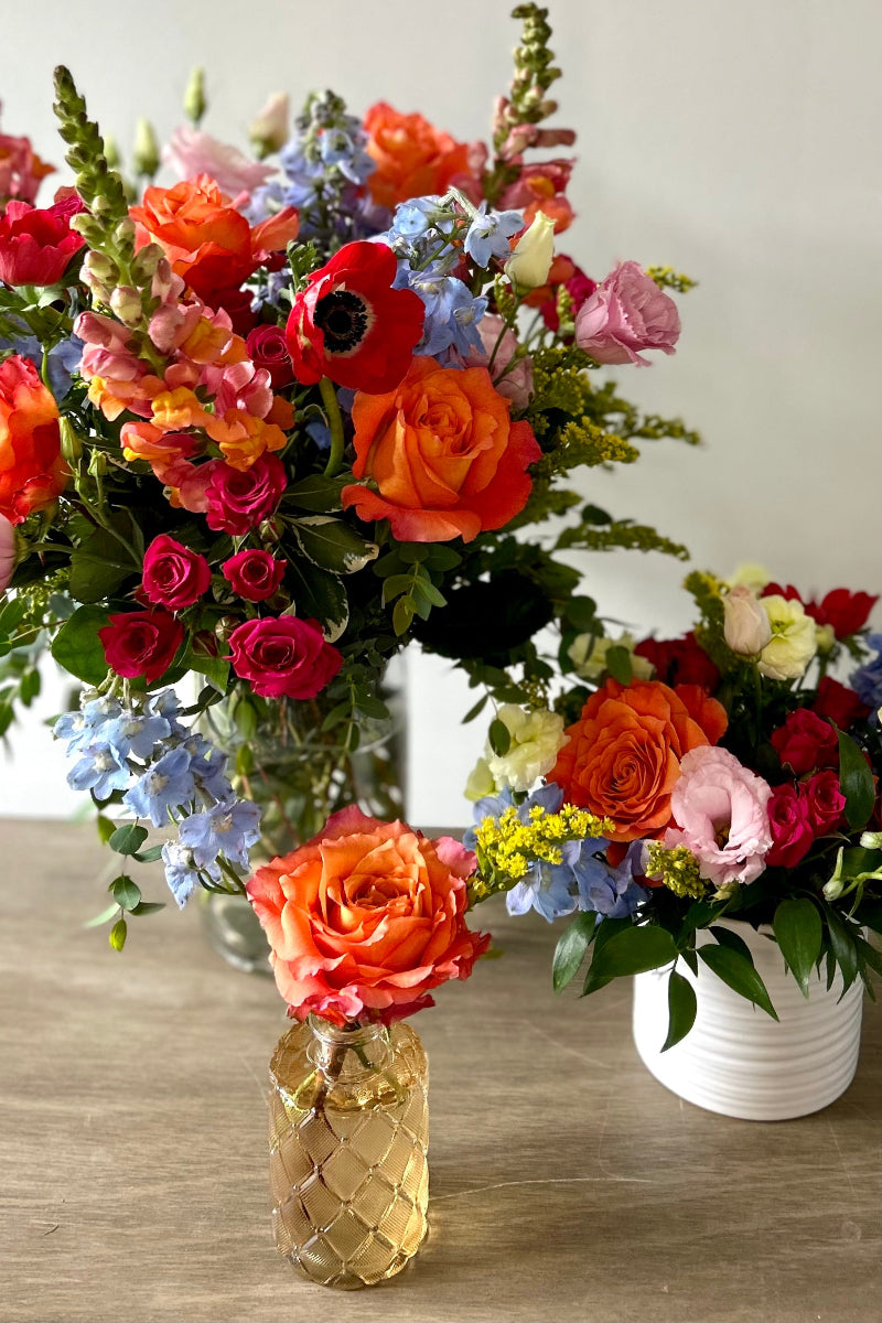 Three colorful flower bouquets in vases ready for a whole house party designed by a local woman owned florist