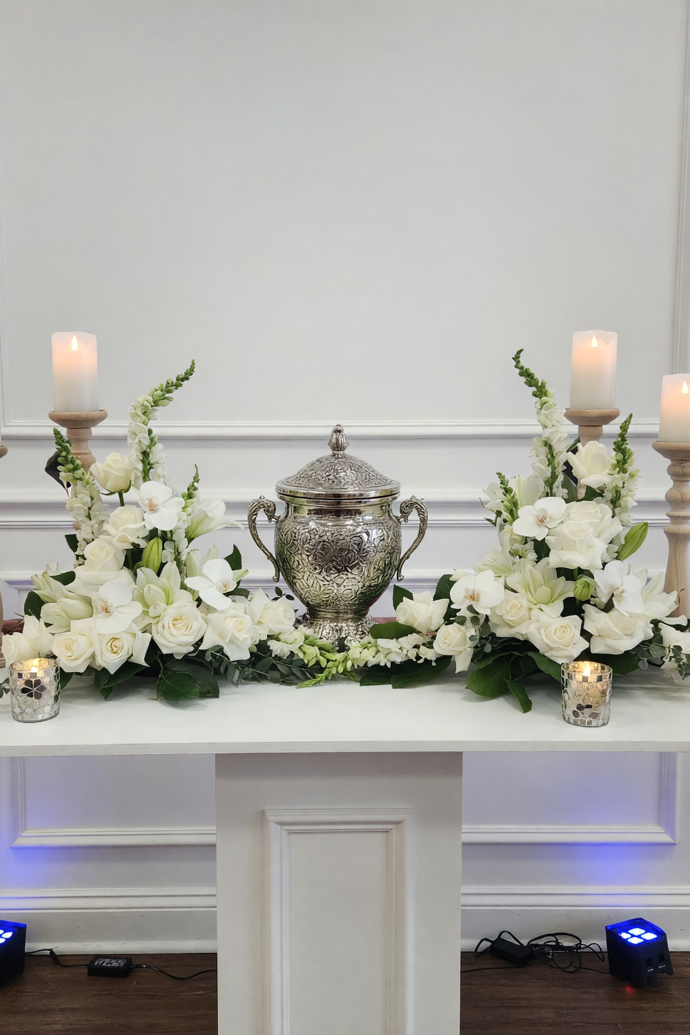 All white Funeral urn flower frame with elegant memorial flowers arranged around an urn, designed by The Flower Fix.