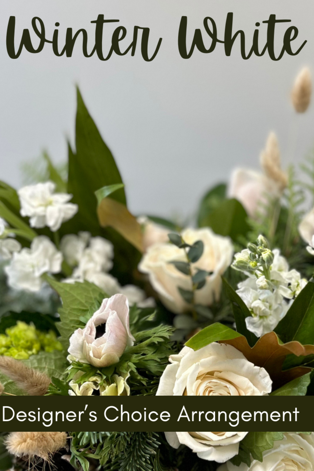 Bouquet of white flowers with green leaves and text &#39;Winter White&#39; and &#39;Designer&#39;s Choice Arrangement&#39;.