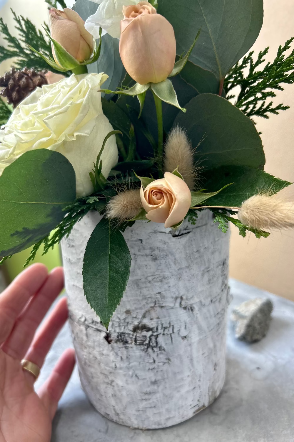 Detail of Winter Whisper Bouquet highlighting natural bunny tail grass, eucalyptus, evergreens, and seasonal foliage with rustic birch bark vase