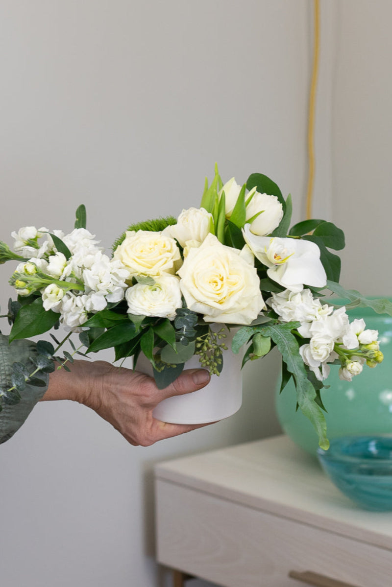 hand holding lush white flower bouquet being delivered for sympathy